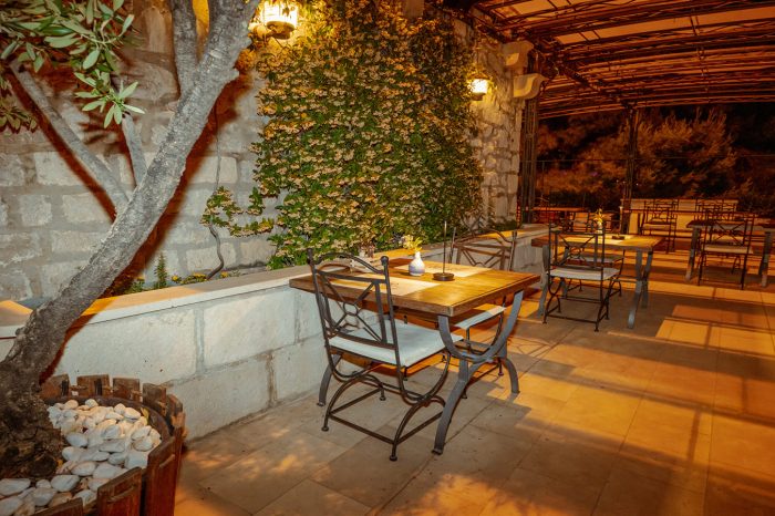 Večer na romantičnoj terasi restorana uz zeleni dekor i maslinovo drvo